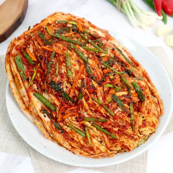 HanMaru bossam-kimchi stuffed with julienned vegetables, chives, and carrots, coated in savory red seasoning on a round plate.