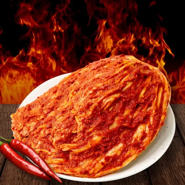 Fiery red “Bul” kimchi from HanMaru on a plate, flames in the background and fresh red chilies in foreground.