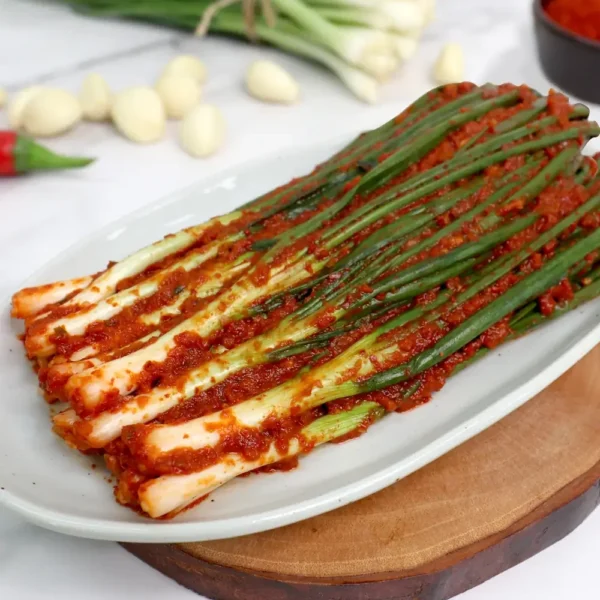 HanMaru pa-kimchi (green-onion kimchi) neatly lined on an oval plate, coated in spicy red marinade.